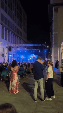 Outdoor band plays under colored stage lights in Livorno night