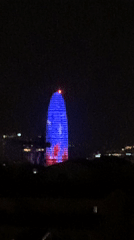 Barcelona's Agbar Tower displays blue-red illumination during evening hours