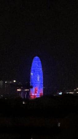 Barcelona's Agbar Tower displays blue-red illumination during evening hours