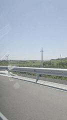 Vehicle travels paved road in Kosh, Armenia during sunny conditions