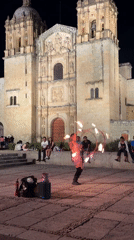Fire dancer performs with flaming props at Oaxaca church plaza