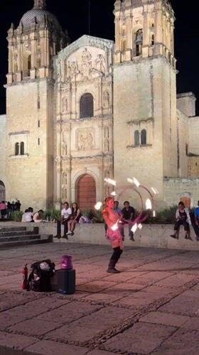 Fire dancer performs with flaming props at Oaxaca church plaza