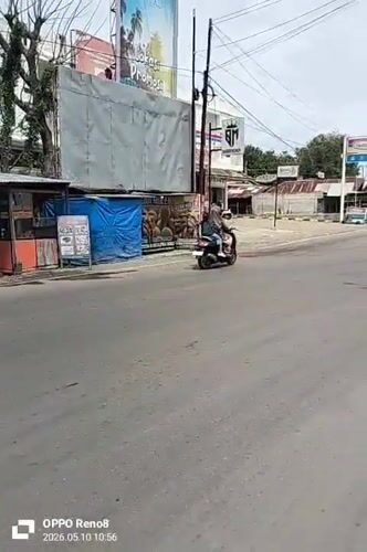 Motorcyclist transports gas tanks through Indonesian commercial district intersection