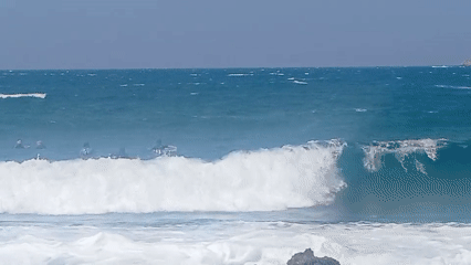 Surfers and beachgoers on a rocky Bandol coastline