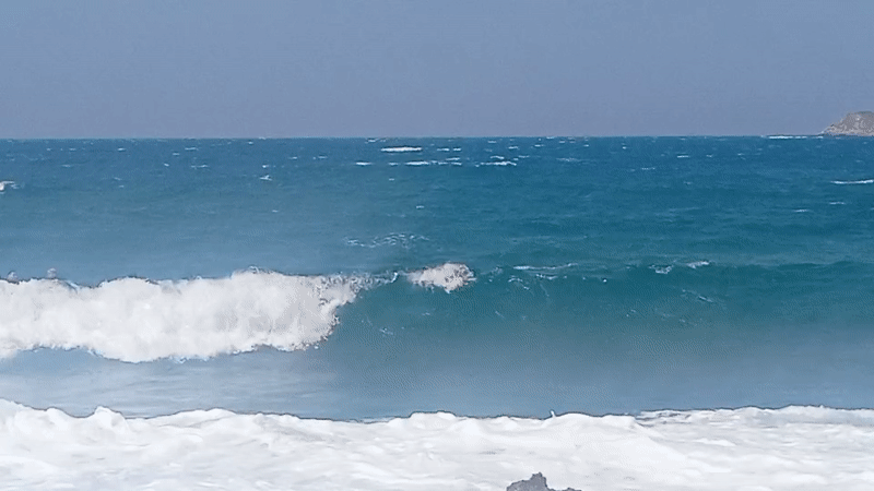Surfers and beachgoers on a rocky Bandol coastline