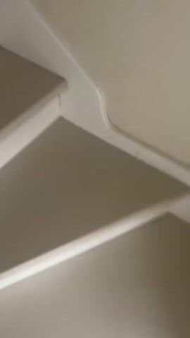 The video shows a close-up view of a staircase. The stairs are carpeted in a light gray color with white risers. The camera pans up the stairs, revealing the wooden floor at the top. The lighting is bright and natural, suggesting the video was filmed during the day. There are no people or other objects visible in the video.