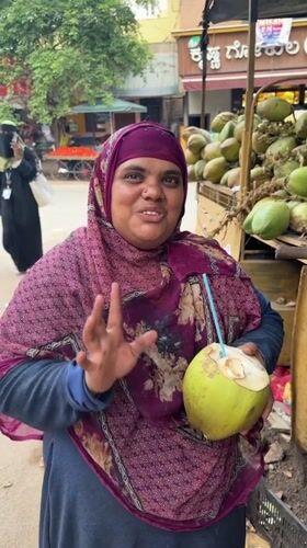 Woman enjoys coconut drink at street vendor in Bengaluru