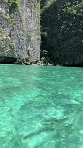 Longtail boat navigates turquoise waters beside Ao Nang's cliffs