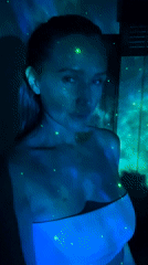 Woman dances in projected nebula lights in Kuta Selatan