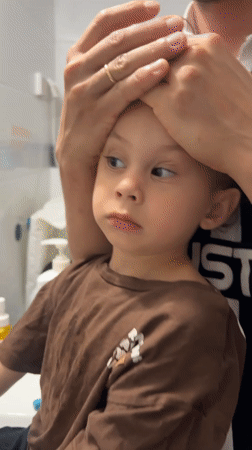 Toddler brushes teeth with adult help in Kiryat Bialik bathroom
