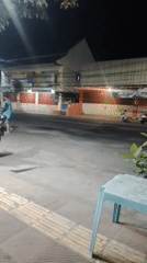 Nighttime street corner with parked scooters and roadside seating