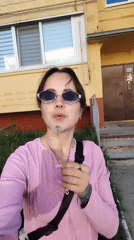 Woman holds dandelion outside yellow building in Noviy, Russia