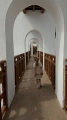 Young girl in polka dot dress walks covered walkway