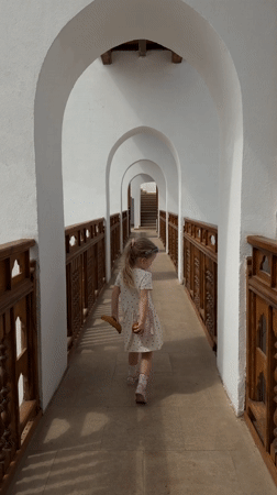 Young girl in polka dot dress walks covered walkway