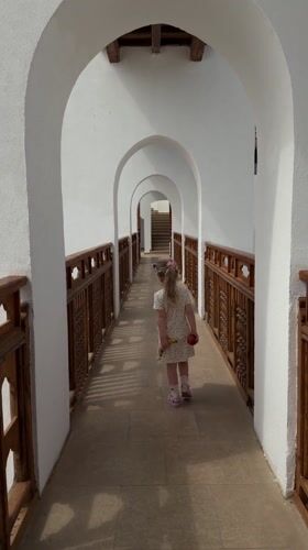 Young girl in polka dot dress walks covered walkway