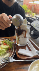 Man pours dark liquid over ice cream in Đà Nẵng