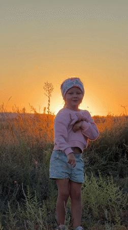 Sunset moment in a Russian wildflower field, arms raised