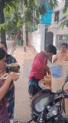 Street vendor serves morning food from sidewalk cart in Dhaka