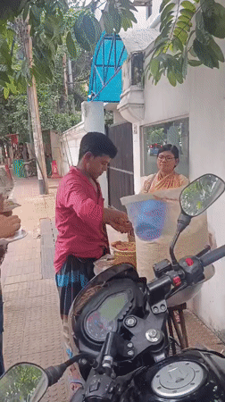 Street vendor serves morning food from sidewalk cart in Dhaka