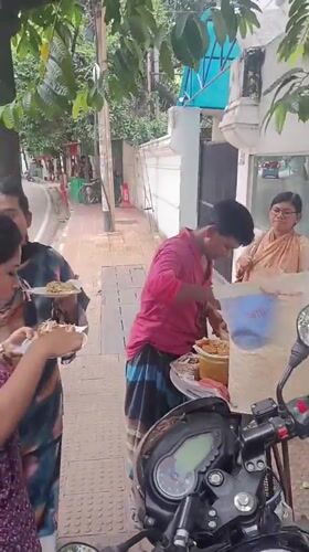 Street vendor serves morning food from sidewalk cart in Dhaka