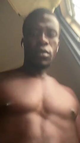 A person's torso, with visible abdominal muscles and chest, is shown in a close-up shot. The person is looking towards the camera, and appears to be wearing white earbuds. The background is out of focus and appears to be an indoor environment.