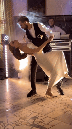 Close dancing in a dimly lit room, dressed in white and dark.