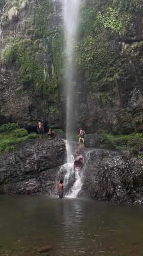 Visitors gather at scenic waterfall near temple in Budar, Nepal