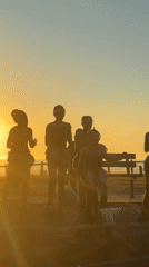 Performance troupe gathers at Cape Town beach during sunset