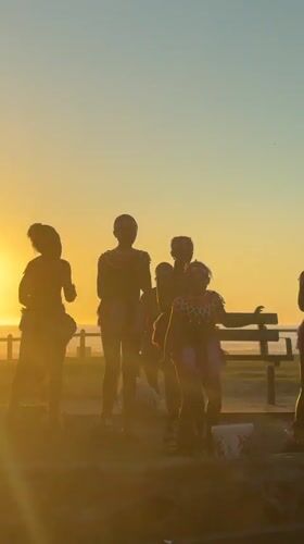 Performance troupe gathers at Cape Town beach during sunset