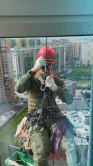 Worker performs rope access maintenance on Russian high-rise building