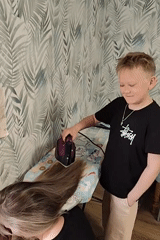 Boy irons wigs, handles cat during domestic morning activities