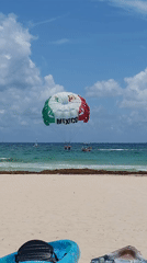 Parasailers display Mexican flag colors over Playa del Carmen waters
