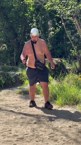 Young men gather in Portuguese woods, one wearing foil hat