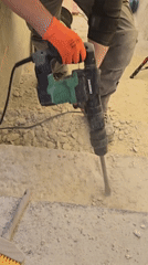 Worker demolishes concrete stairs with jackhammer, laser guidance