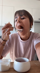 Woman enjoys yogurt breakfast in Cannes kitchen Sunday morning