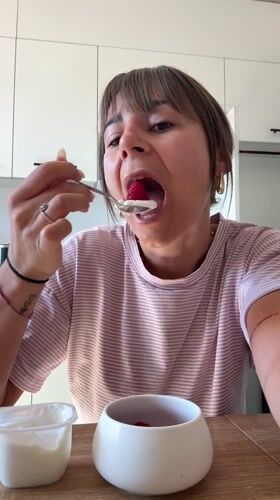 Woman enjoys yogurt breakfast in Cannes kitchen Sunday morning