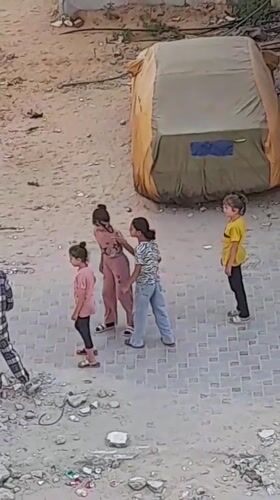Children on a paved area near a large tent in Khan Yunis