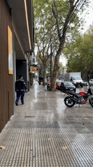 Uniformed man walks wet Buenos Aires streets during rainfall