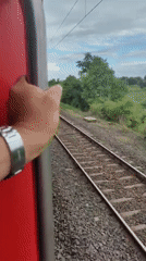 Holding on tight to a red train rolling through Malkapur