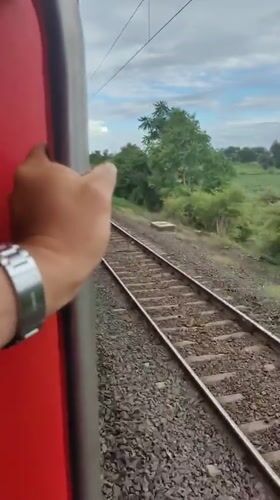 Holding on tight to a red train rolling through Malkapur