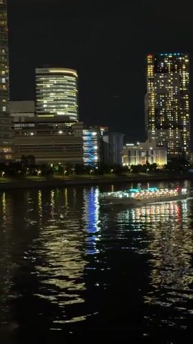 Illuminated boat crosses Tokyo waterway at night