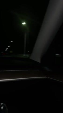 The video captures a nighttime journey from the perspective of inside a moving car.

**Subjects:** No people are explicitly visible, but the viewpoint suggests a passenger or driver in the vehicle.

**Objects:** The car's interior is partially seen, including a dark dashboard and a window frame. Outside, distant streetlights illuminate the dark road. A prominent object is the car's infotainment screen or a similar device, which displays navigation and vehicle data.

**Scene and Setting:** The scene unfolds at night, with streetlights piercing through the darkness. The car is actively driving on a road, as indicated by the blurred lights in motion and the displayed speed. The navigation system on the screen places the setting in or near "Dimitrov, Armenia," with "Holy Mother of God Church" and "ADANA RESTORANT" marked as points of interest.

**Activity or Event:** The primary activity is driving at night. The car is moving at a consistent speed, and music is playing in the background throughout the duration of the video.

**Notable Details:**
*   **Time of day:** Night.
*   **Speed:** The vehicle is traveling at 84 km/h.
*   **Time:** The current time displayed on the screen is 20:48.
*   **Temperature:** The recorded temperature is 18°C.
*   **Location Cues:** The navigation map clearly indicates "Dimitrov," "Armenia," "ADANA RESTORANT," and "Holy Mother of God Church."

**Visible Text:** The screen displays "84" (speed), "20:48" (time), "18°C" (temperature), "ADANA RESTORANT," "Holy Mother of God Church," and "Dimitrov." Text related to playing music, possibly "Auto Reverse," is also partially visible on the screen.