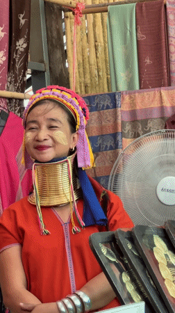 Man gestures on dirt path as group walks in Thailand village