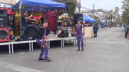 Street drummers in purple perform at an outdoor festival in Arica