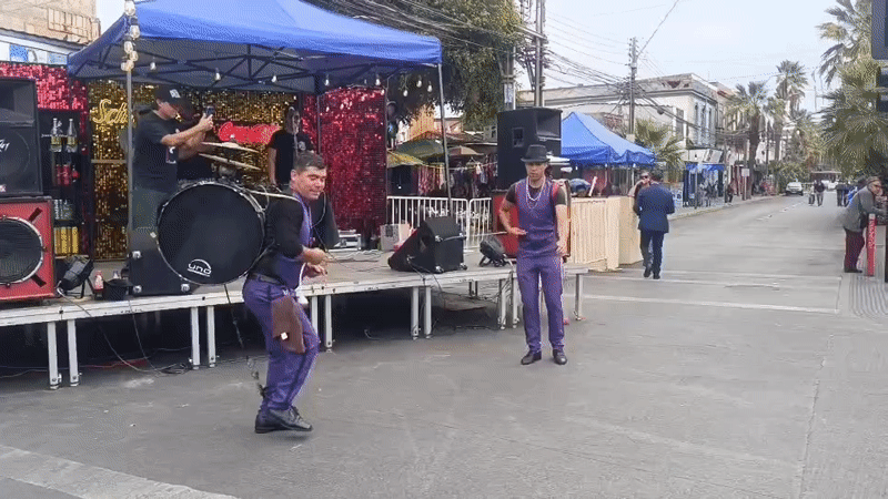 Street drummers in purple perform at an outdoor festival in Arica