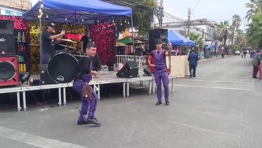 Street drummers in purple perform at an outdoor festival in Arica