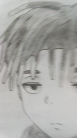 The video is a close-up shot of a pencil sketch of a young male with dreadlocks. He is wearing a denim jacket over a hoodie with a skull design on it. The sketch is detailed and realistic, capturing the texture of the hair and clothing. The background is a plain white surface. A signature appears to be present on the right side of the drawing.