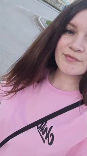 Woman films selfie video on Tobolsk street amid everyday pedestrian activity