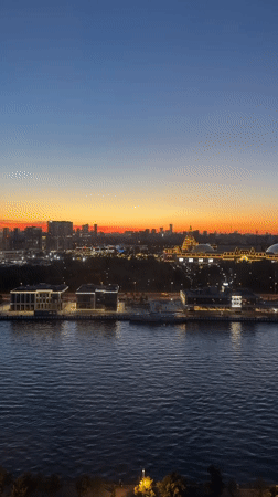 Moscow River skyline glows at dusk under a crescent moon