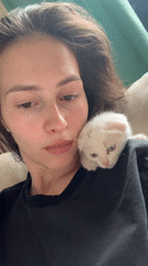 Woman holds white kitten, electronic device in Yekaterinburg home